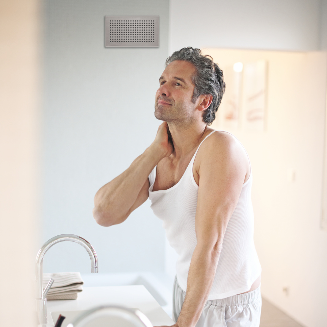 Bouche d'évacuation d'air dans la salle de bain. Homme devant un miroir